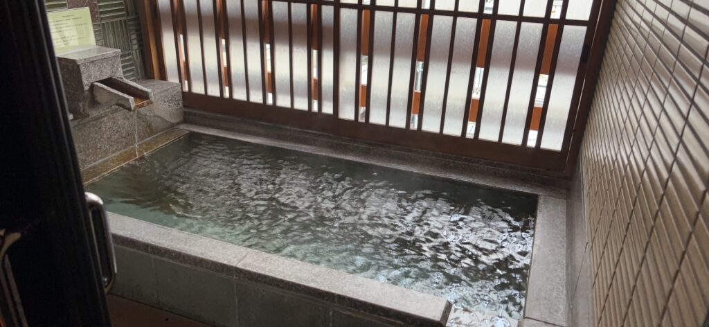 佳翠苑 皆美の露天風呂。石造りの浴槽に湯口から湯が注がれている